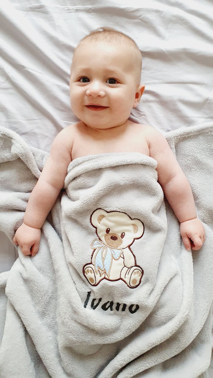 Ein süßer kleiner Junge, bedeckt mit einer weichen, personalisierten Decke