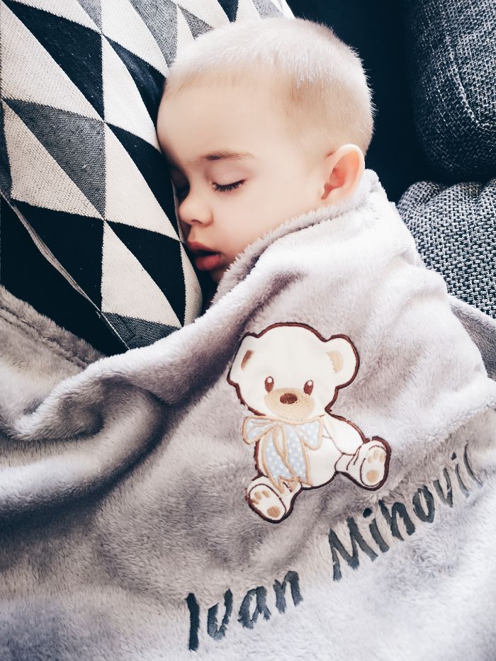 Little boy sleeping covered with his personalized gray blanket