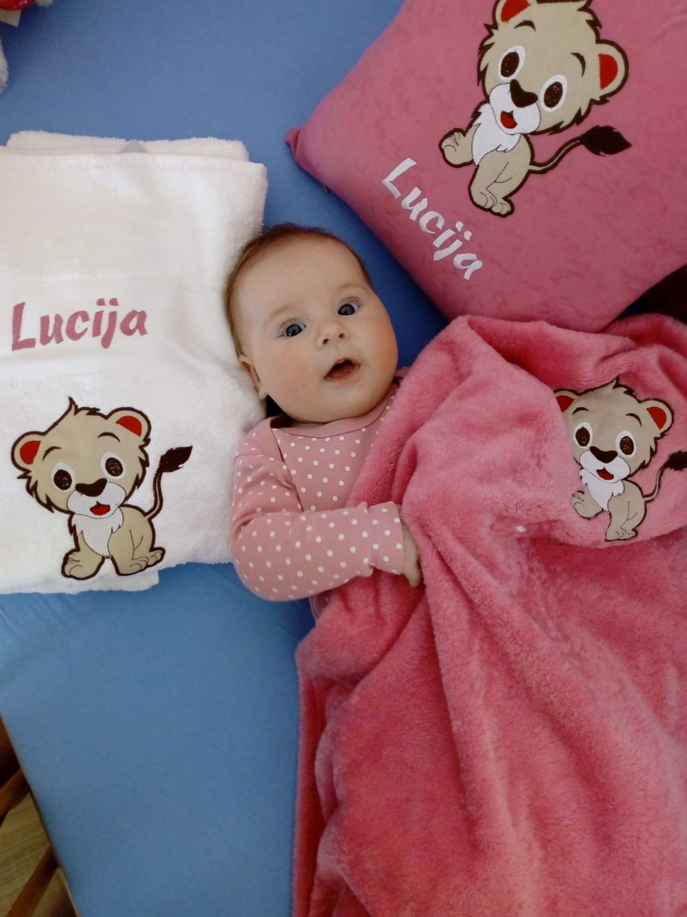 Schattige baby meisje geniet van haar gepersonaliseerde set bestaande uit een kussen, deken en handdoek, allemaal aangepast met haar naam.