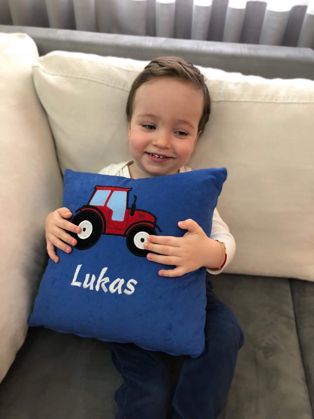 The boy proudly shows off his personalized cushion, with a vibrant design and his name on it.