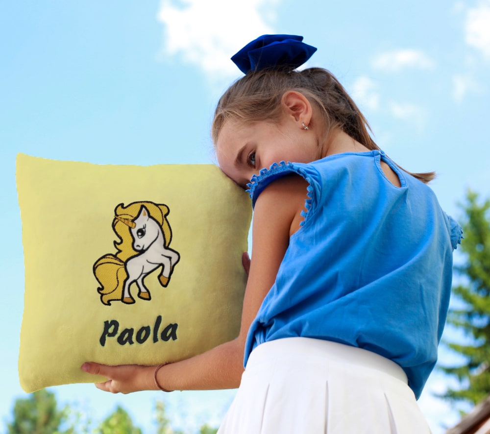 The little girl proudly shows off her personalized cushion, with a vibrant design and her name on it.
