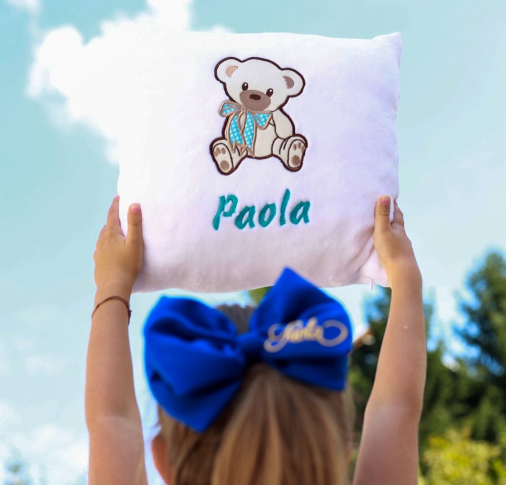 The little girl proudly shows off her personalized cushion, with a vibrant design and her name on it.