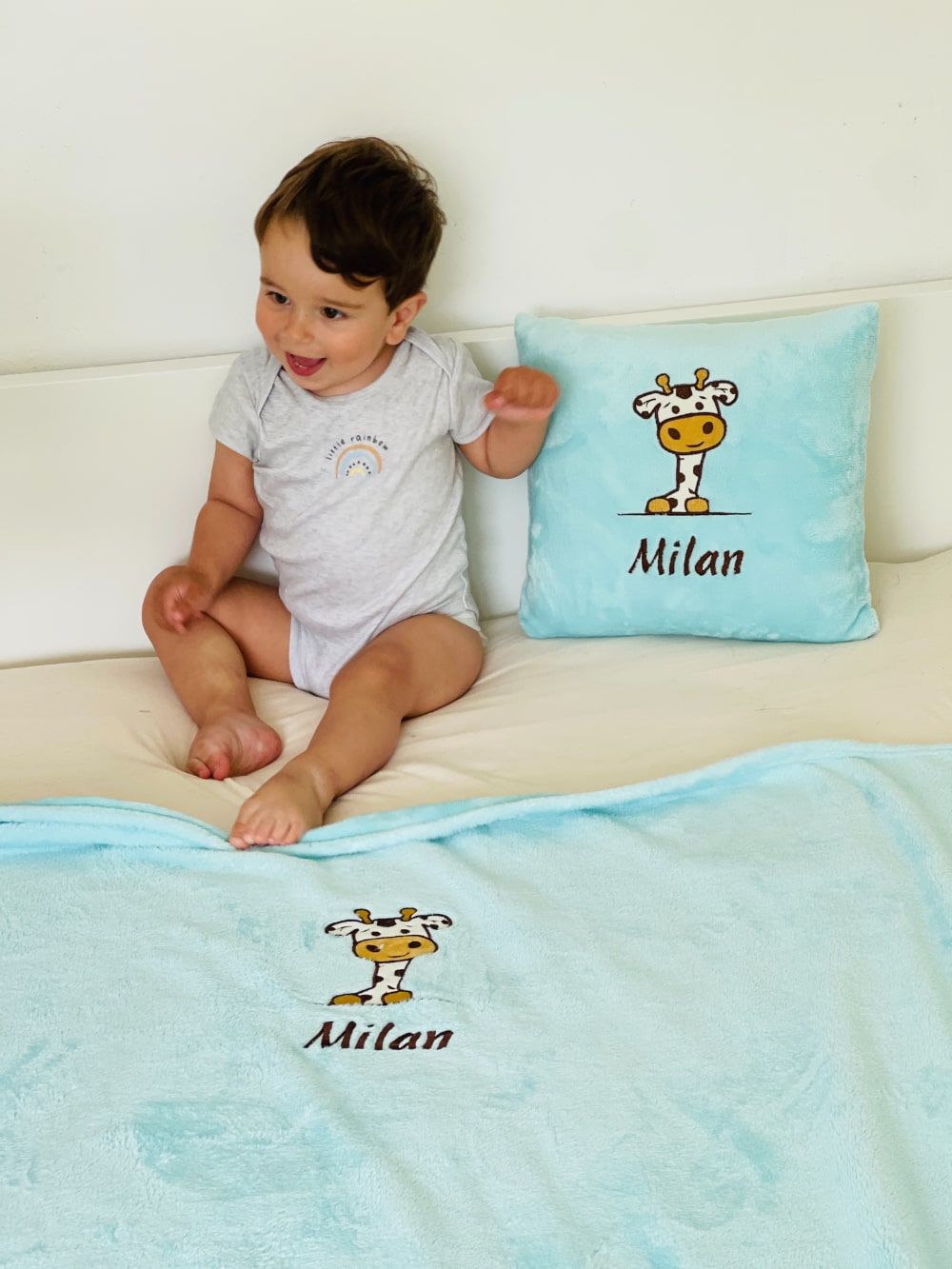 Adorable boy rests peacefully on his bed, snuggled up with a soft and cozy personalized pillow and blanket, customized with his name and a charming design.