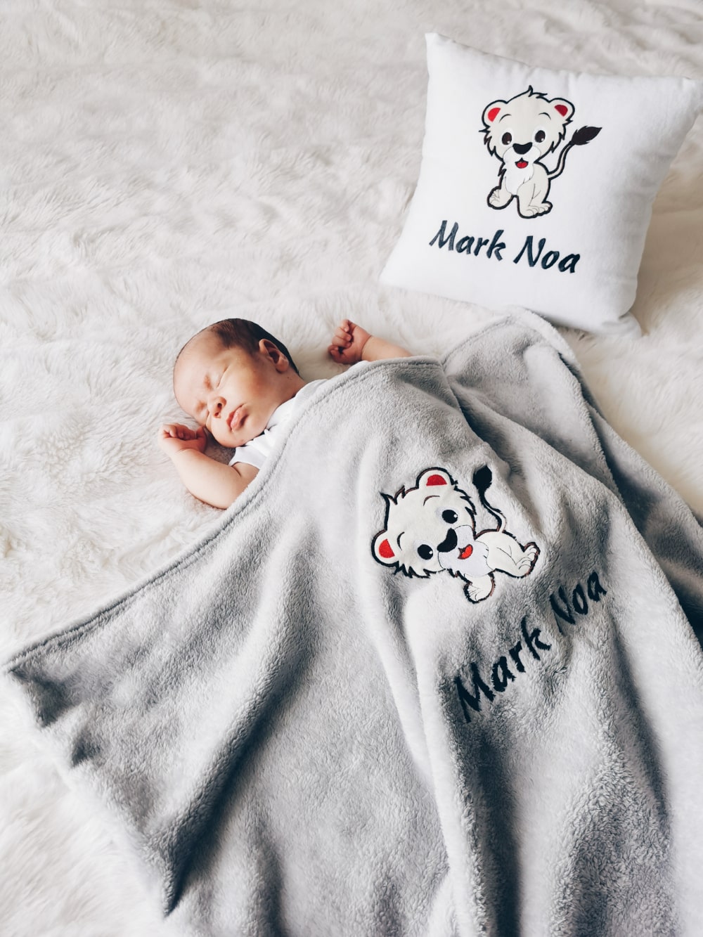 Adorable baby boy rests peacefully on his bed, snuggled up with a soft and cozy personalized pillow and blanket, customized with his name and a charming design.
