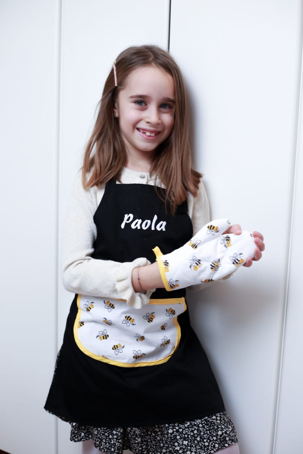 Jong meisje geniet van haar gepersonaliseerde schort en ovenwanten