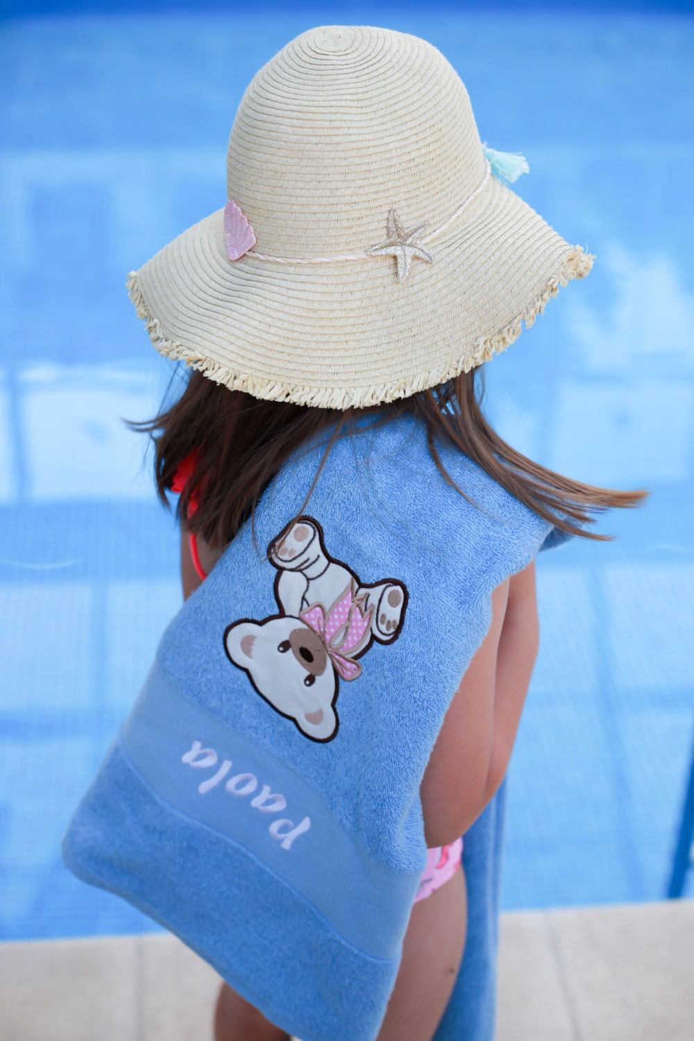 Het kleine meisje laat trots haar gepersonaliseerde handdoek zien, met een levendig ontwerp en haar naam erop.
